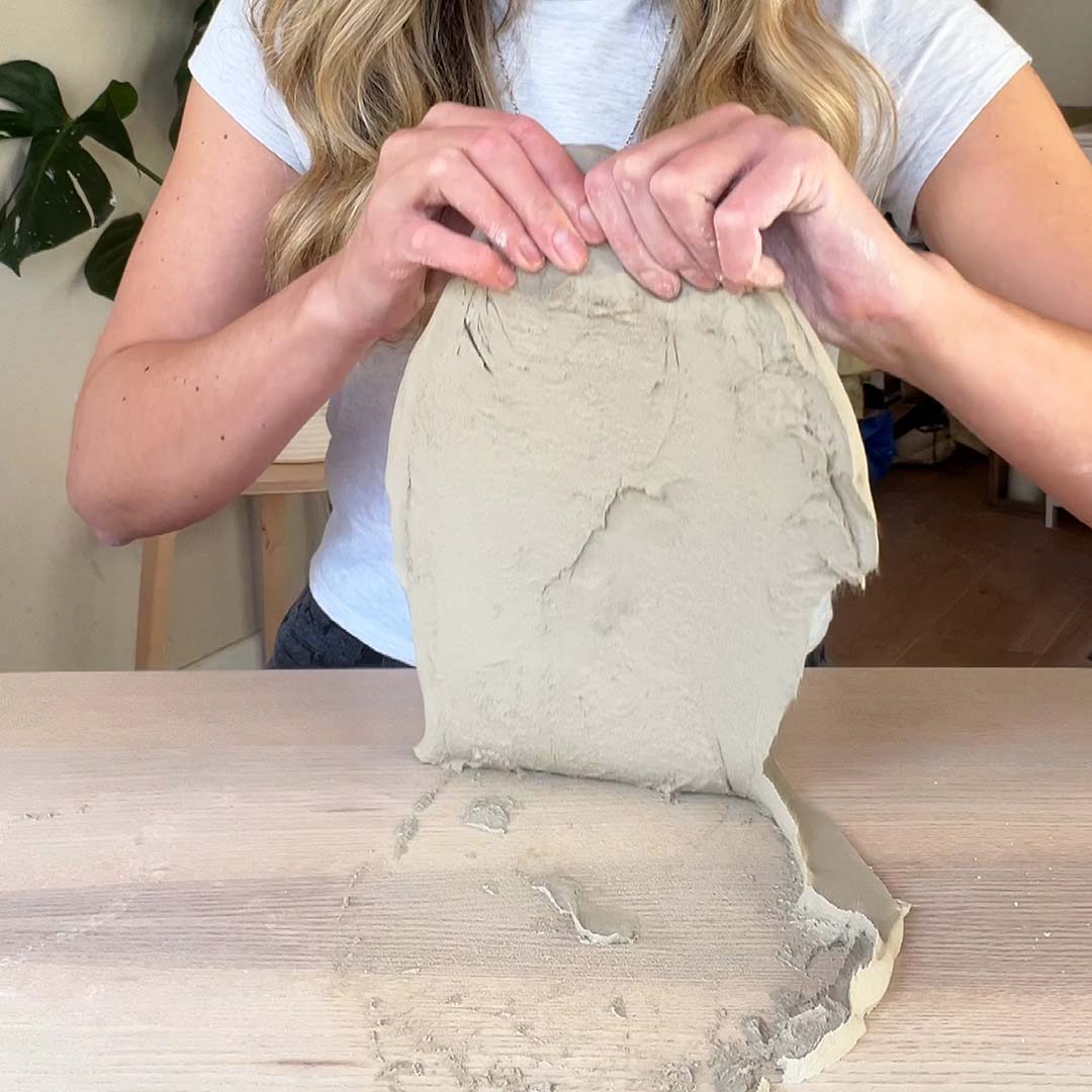 An artist holds aloft a slab of clay made using Sculpd Pottery Kit
