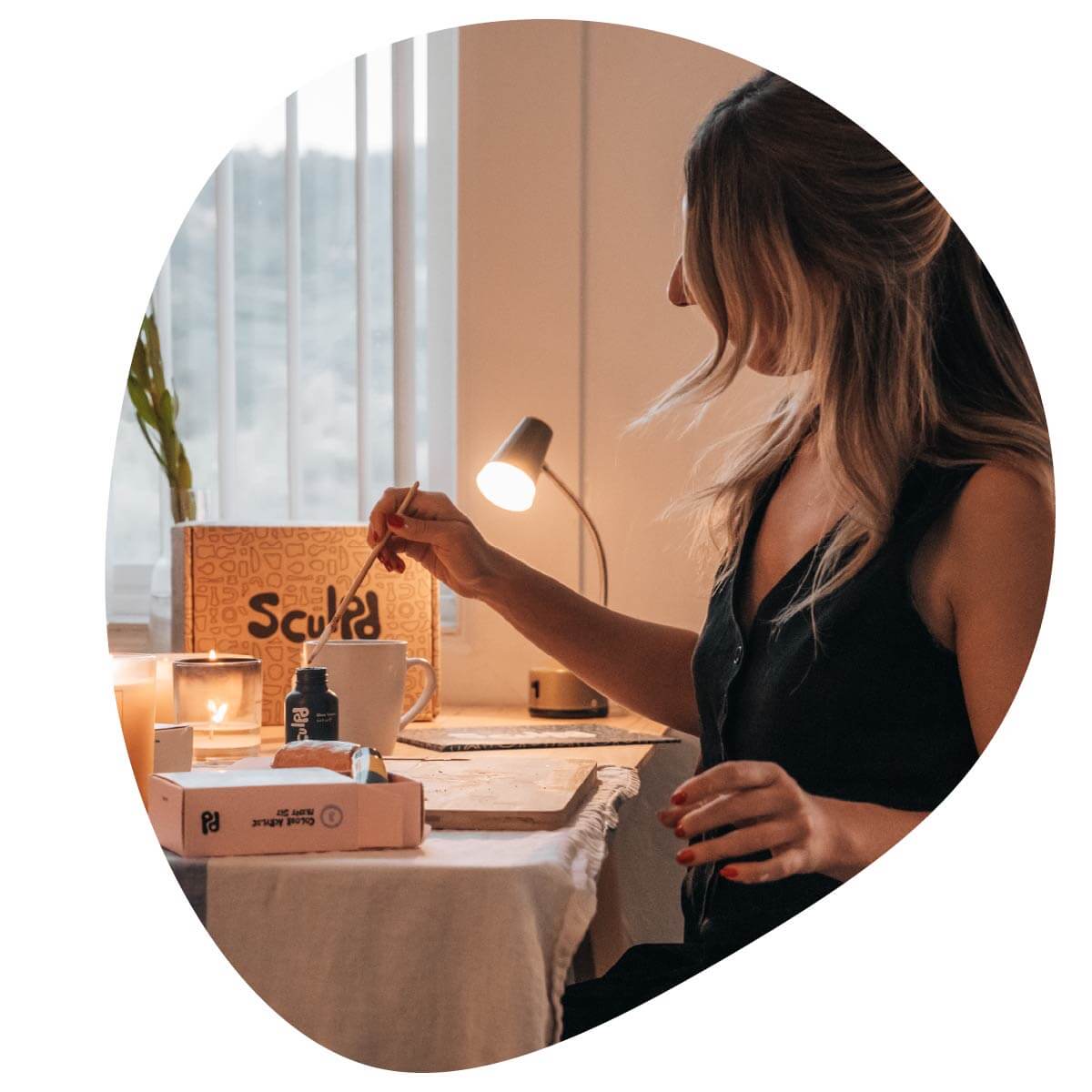 Woman with the Sculpd Pottery Kit on a table with a lamp