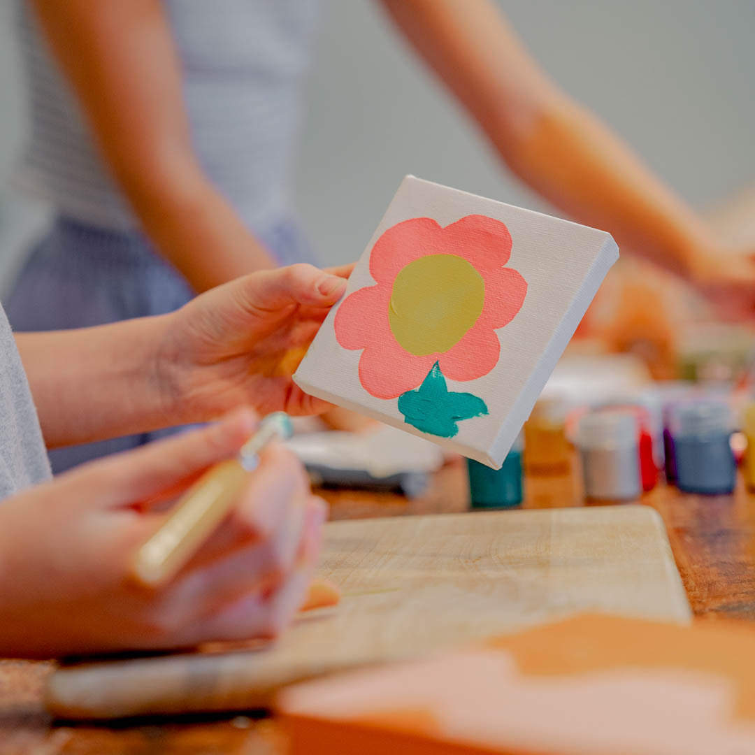 Child's hands painting a flower on her canvas mini easel painting