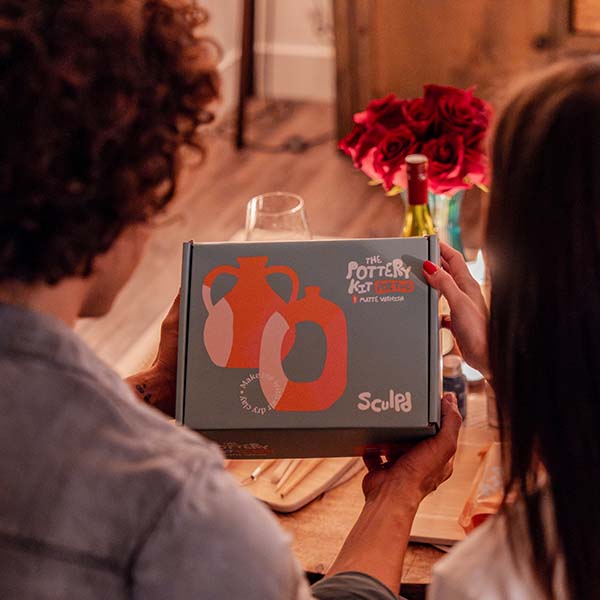 Sculpd Pottery Kit For Two held aloft by two people with a stylized background