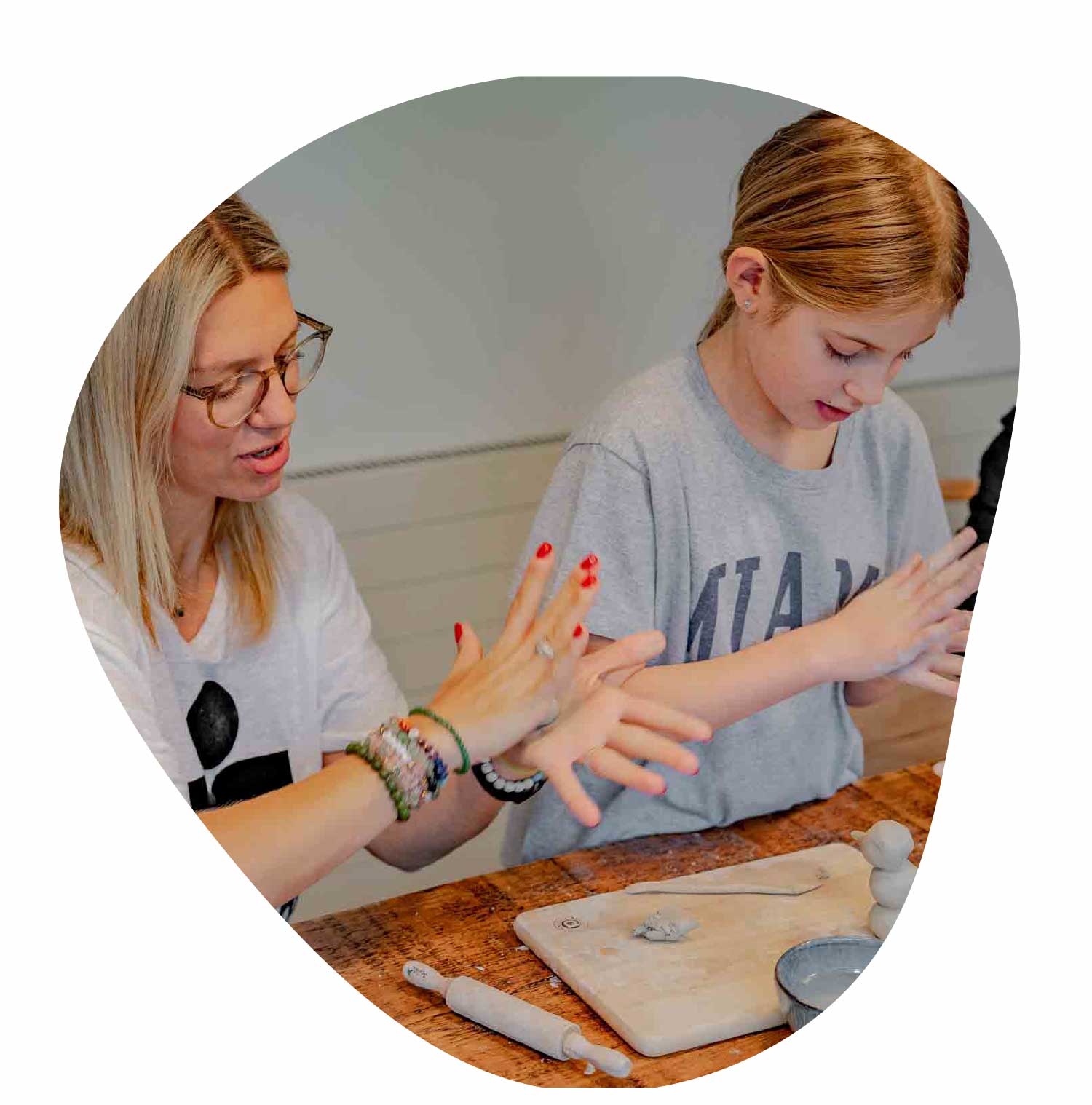 A child and her mom doing pottery together at the kitchen table